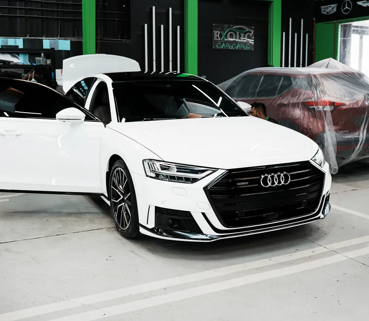White Audi A8 with its door open in the Exotic Auto Services detailing bay in Mussafah, Abu Dhabi.