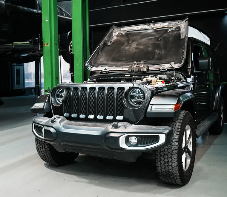 Jeep Wrangler with the bonnet raised for engine bay inspection at the Exotic Auto Services workshop in Mussafah, Abu Dhabi.