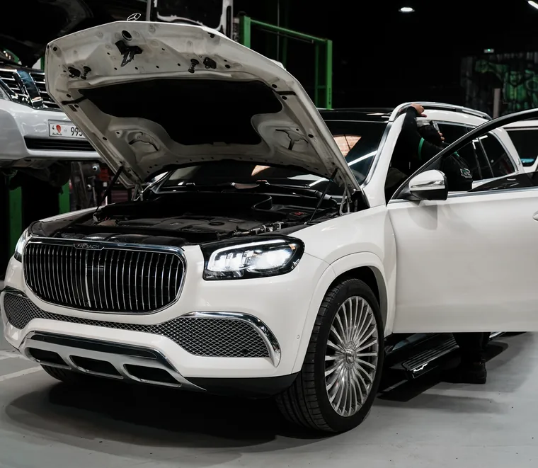 White Mercedes-Maybach GLS with the bonnet and door open in a service bay at Exotic Auto Services in Abu Dhabi.