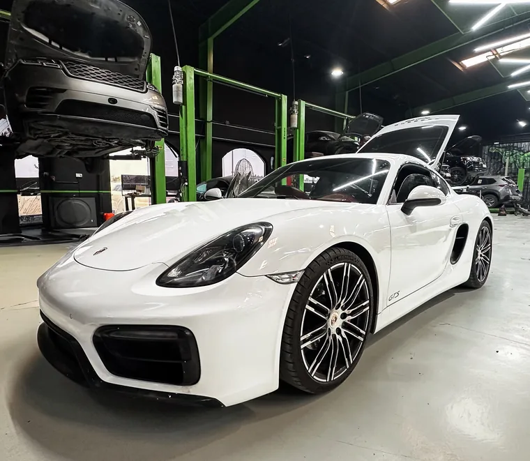 White Porsche Cayman GT4 in the detailing bay at the Exotic Auto Services workshop in Abu Dhabi.