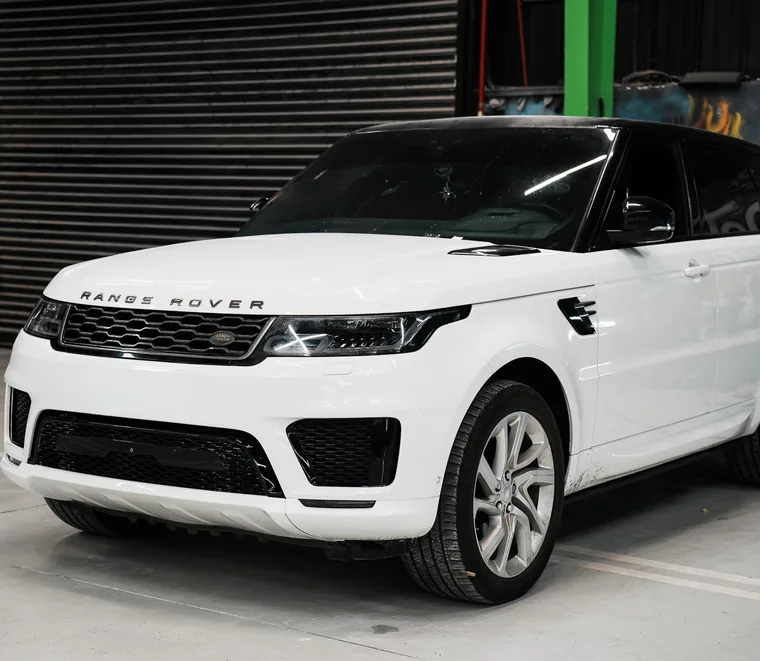 White Range Rover Sport in a service bay at the Exotic Auto Services workshop in Abu Dhabi.