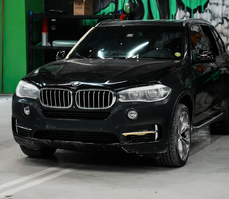 Black BMW X5 in a service bay at the Exotic Auto Services workshop in Abu Dhabi.
