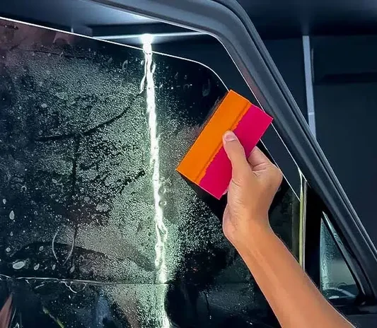 Window tint film being applied to a car at the Exotic Auto Services workshop in Mussafah, Abu Dhabi