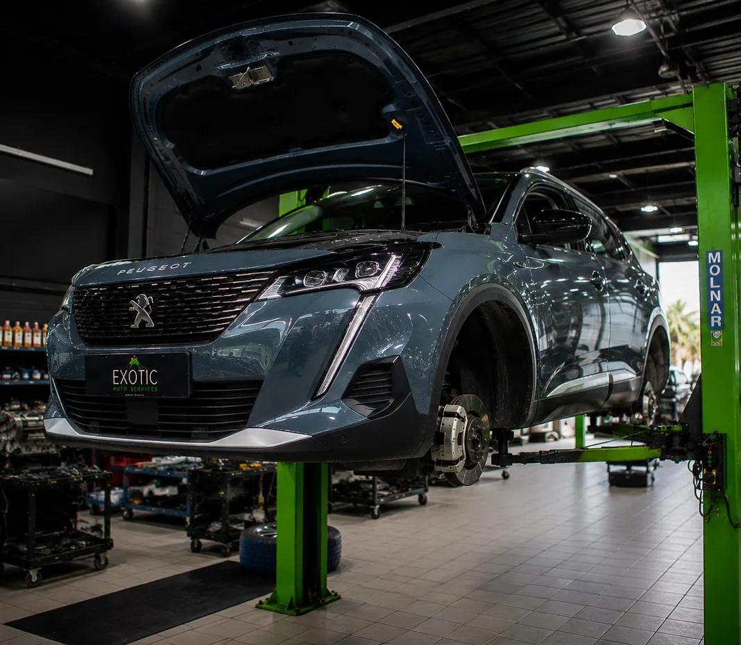 Peugeot with the wheels off for brake service at the Mussafah workshop